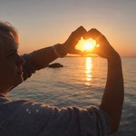 Campingplatz Zierow Person formt mit den Händen ein Herz um die untergehende Sonne am Meer bei warmem Abendlicht